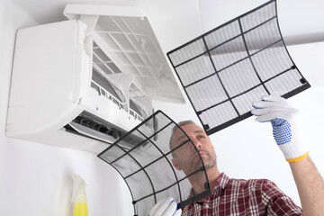 Service guy cleaning and maintaining air condition unit.
