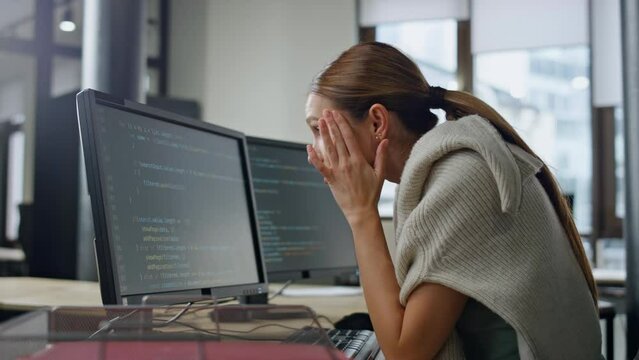 Exhausted developer working office alone. Stressed woman rubbing head searching