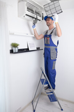 Service guy cleaning and maintaining air condition unit.