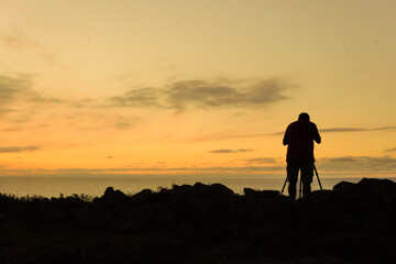 Fototapeta na wymiar silhouette photographer taking photo with professional camera in sunset. Photography day