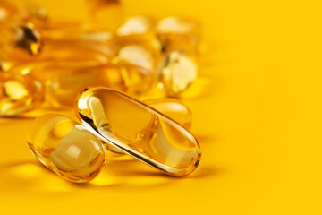 two capsules Omega 3 on yellow background and many other of capsules on blurred background. Health care concept
