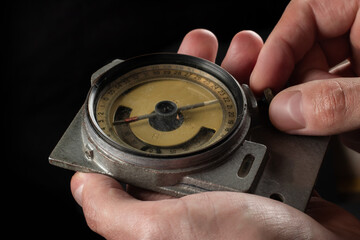 Old mining compass in hand on dark background close up
