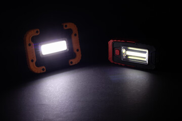 Closeup pocket LED flashlight on dark background. © eliosdnepr