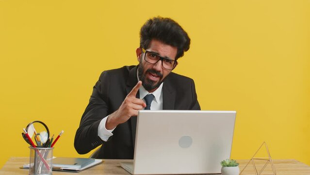 Quarrel. Displeased angry mad indian businessman gesturing hands with irritation and displeasure, blaming scolding for failure, bad fail work job at office workplace. Hindu man on yellow background