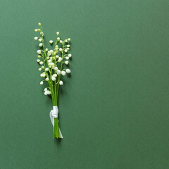 Bouquet of white lilies of the valley. Empty mockup copy space on neutral green paper background. Minimal aesthetic wedding and birthday invitation template. Flat lay, top view