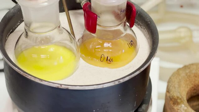Colourful reactions under heating condition in sand bath. 4K video experiments in a chemistry lab. Biochemical medicine synthesis in the laboratory.