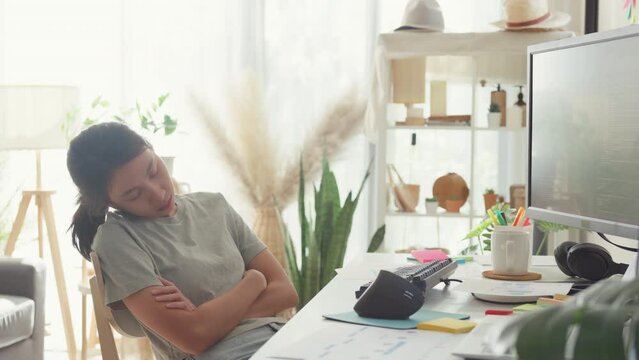Young Asia girl development programmer overwork fall asleep on her desk next to computer upload coding program database on computer at house office. Workaholic suffering mental health concept.