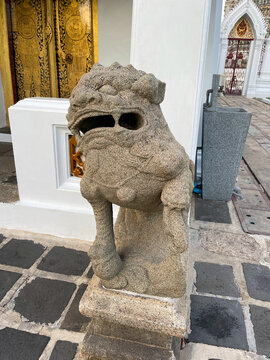 Foo Dog Antique Chinese Statue in front of the door. Chinese lion dog sculpture. Antique symbol. Buddhist temple. Wat Arun territory, outdoors area. Bangkok city. Capital of Thailand. Asian culture.