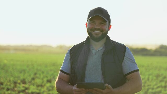 Botanist agronomist man with tablet on farm field checks inspects plants growth and collects data. Worker compiles report of plant cultivation. Caucasian male on farmland controls planting seedlings.