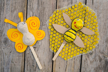 Craft from the packaging of egg trays - a bee and butterfly on an ice cream stick against a...
