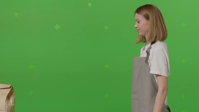 The waiter hands the package of food to the delivery man on green screen chroma key background.