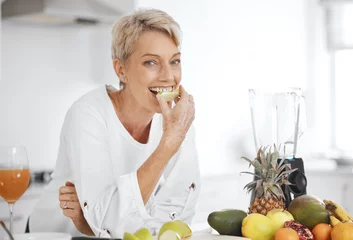 Plexiglas foto achterwand Portrait, fruit salad and apple with an elderly woman in the kitchen of her home for health, diet or nutrition. Smile, food and cooking with a happy senior female pensioner eating healthy in a house © Felix/peopleimages.com