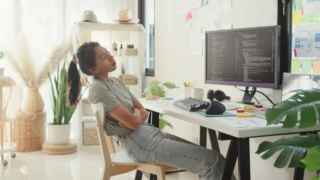 Young Asia girl development programmer overwork fall asleep on her desk next to computer upload coding program database on computer at house office. Workaholic suffering mental health concept.
