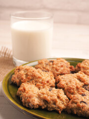Fresh organic milk and tasty oatmeal cookies on a white wooden table