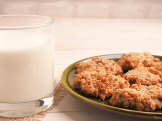 Fresh organic milk and tasty oatmeal cookies on a white wooden table