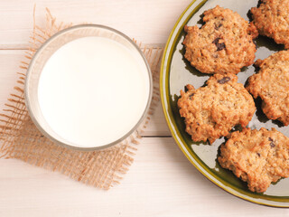 Fresh organic milk and tasty oatmeal cookies on a white wooden table, view from above
