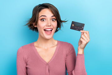 Photo of astonished pretty girl hand hold plastic debit card isolated on blue color background