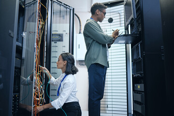 Server room, engineer and IT team with a tablet for programming, cybersecurity or cable maintenance. Man and woman technician together in datacenter for network, software or system upgrade with tech - Powered by Adobe