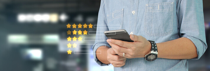 Man holding smartphone device and touching screen with five star rating feedback