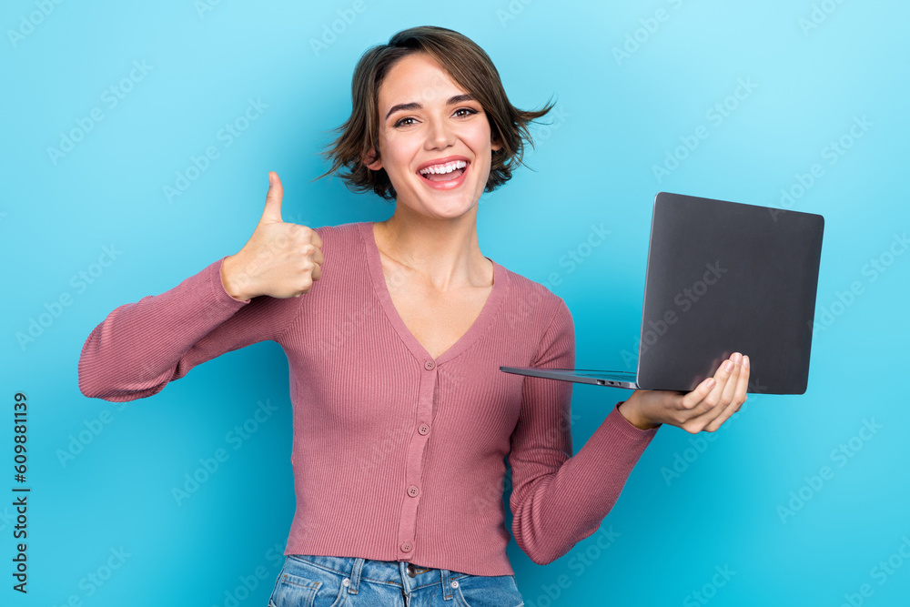 Poster portrait of charming excited person hold netbook demonstrate thumb up feedback isolated on blue colo
