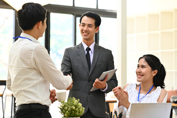Two smiling businessmen shaking hands after successful negotiations at meeting