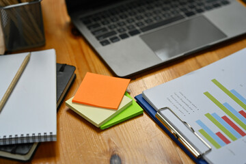 Colorful sticky notes, financial document, notebook and laptop computer on wooden table in office
