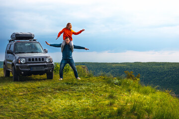A couple in love fooling around, having fun, good mood on a trip, vacation. old SUV car, trip at warm summer day. Man and woman enjoying time together travelling by vehicle. Copy space. Ukraine