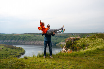 Happy in love couple man holds a woman in his hands, throws her up. travel hiking together among the mountains looking for adventure enjoy the local nature. Dniester river canyon, Subich, Ukraine