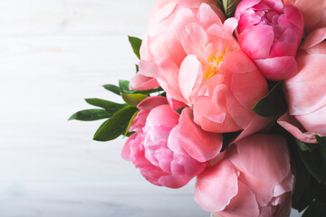 Beautiful bouquet of fresh coral pink peony flowers in full bloom on white wooden background, view from above.