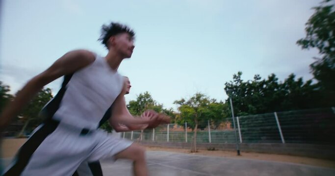 Super wide angle shot of two friends or rivals play street basketball outside in park. Urban street sport. Youth free time development program activity. Active and healthy lifestyle