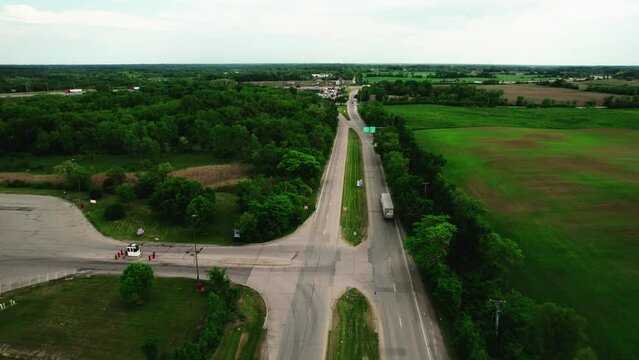 beautiful aerial of a dry van semi truck trailer entering a ramp of a highway sorounded by green environment. Cinematic aerial, Wisconsin USA 4k