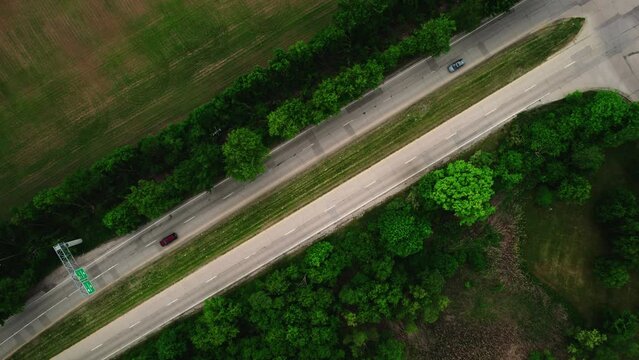 top down aerial of a road in USA very symetric and full of green environement. 2 cars driving under a sign road. Wisconsin, USA