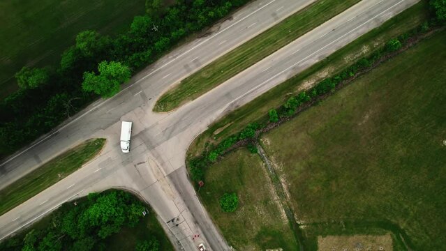 top down of trucking transportaions driving on a road sorounded by beautiful green in the summer. Small box track and tractor trailer dry van. Aerial 4k
