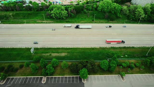 aerial of a interstate highway at the rush hour with cars, semi truck and trailers driving to deliver cargo