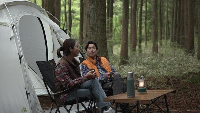 텐트 앞에 나란히 앉아 편안하게 휴식하는 부부