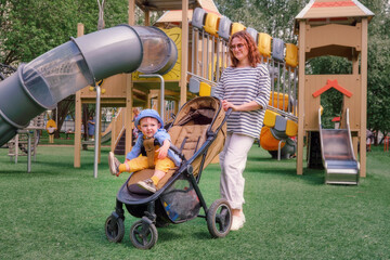 The woman and toddler baby are enjoying the warm summer breeze while walking with their pushchair....