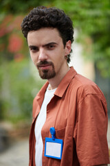 Portrait of bearded converence visitor with badge on shirt standing outdoors