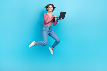 Fototapeta na wymiar Full length portrait of energetic pretty person jumping use netbook isolated on blue color background