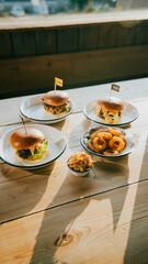 a wooden table topped with plates of snacks, burger, fries. 