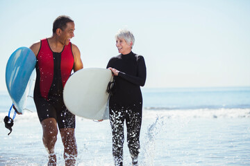 Senior couple with surfboards on beach
