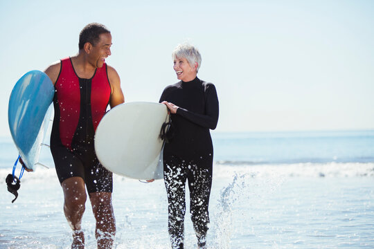 Senior couple with surfboards on beach