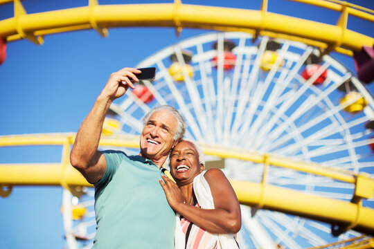 Senior couple taking selfie at amusement park