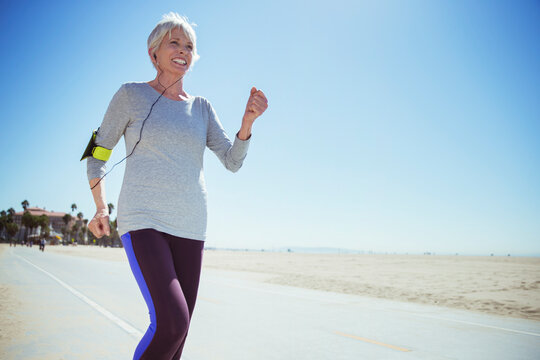 Senior woman jogging on beach boardwalk