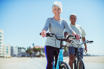 Portrait of senior couple with bicycles on beach boardwalk