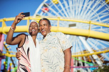 Senior couple taking selfie at amusement park