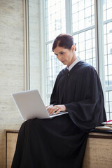 Judge sitting on bench using laptop in courthouse