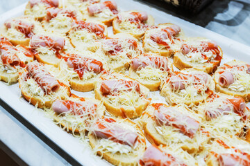 Delicious variety of gourmet canapes, ham and grated cheese, on a decorative board at the restaurant at a wedding or corporate party. Decorated serving board.