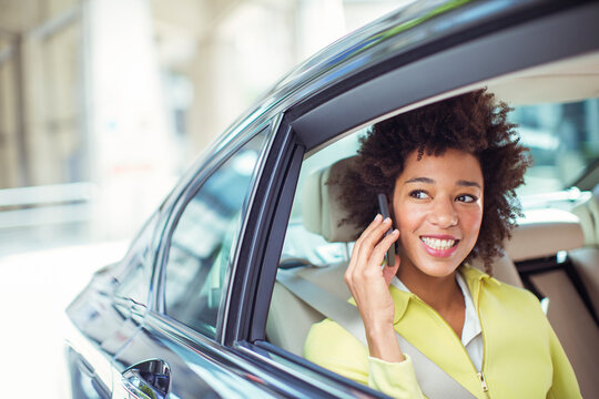 Businesswoman Talking On Cell Phone In Back Seat Of Car