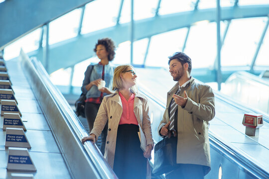 Business people talking on escalator - Powered by Adobe