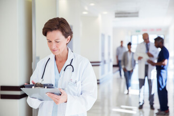 Doctor using digital tablet in hospital corridor - obrazy, fototapety, plakaty